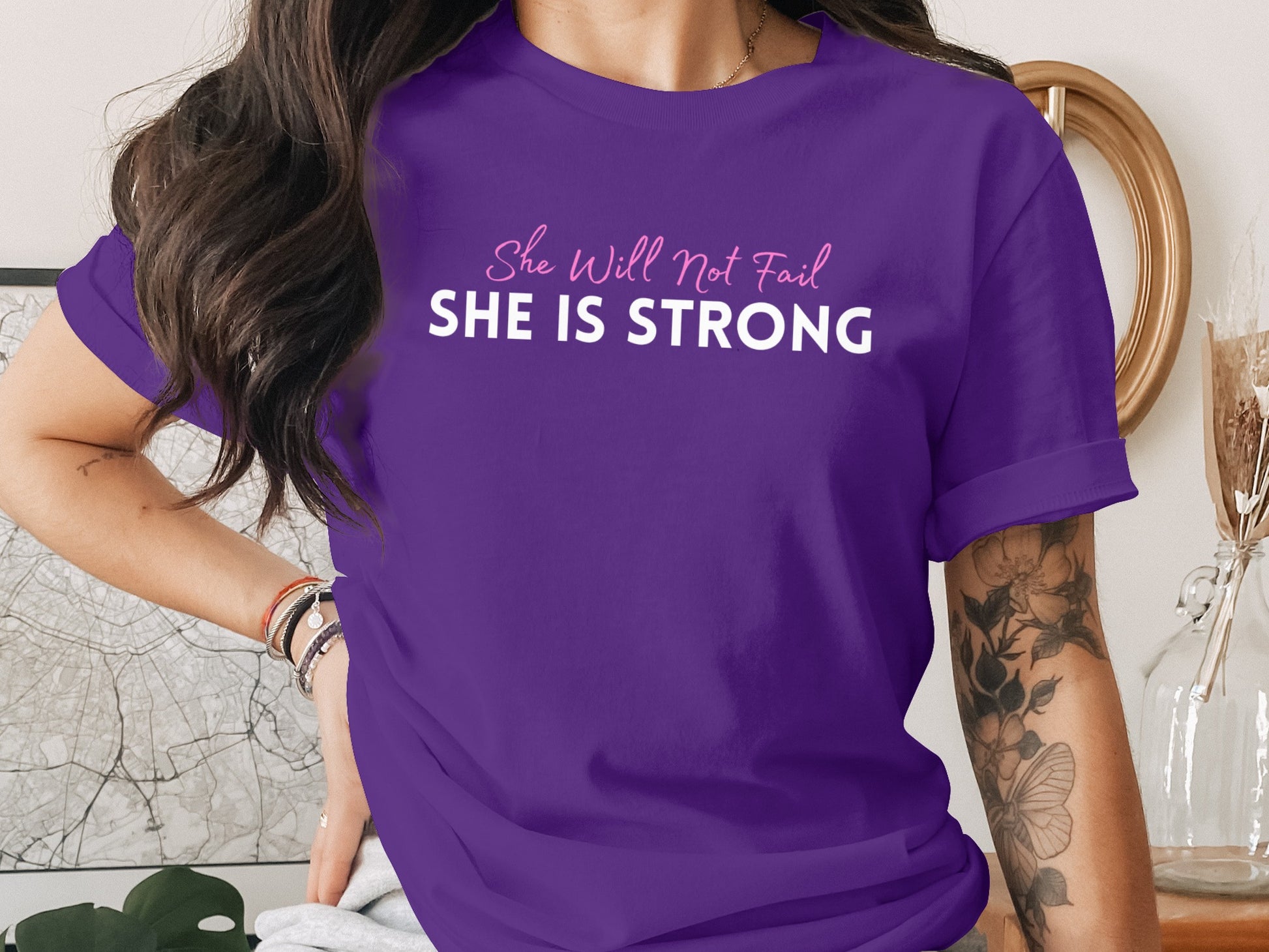 Purple t-shirt with "She Will Not Fail SHE IS STRONG" text.