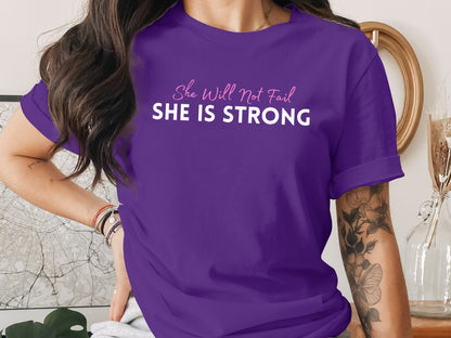 Purple t-shirt with "She Will Not Fail SHE IS STRONG" text.