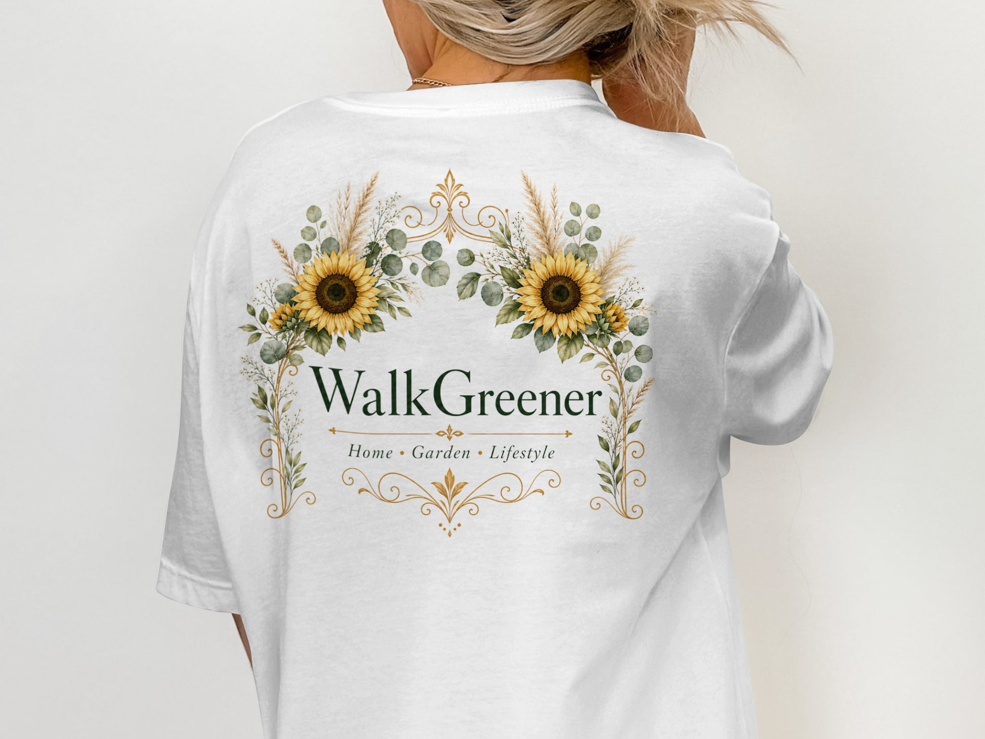 White t-shirt with a floral emblem featuring sunflowers and the text "WalkGreener Home Garden Lifestyle".