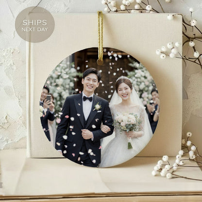 Round ornament with smiling bride and groom, covered in falling petals.