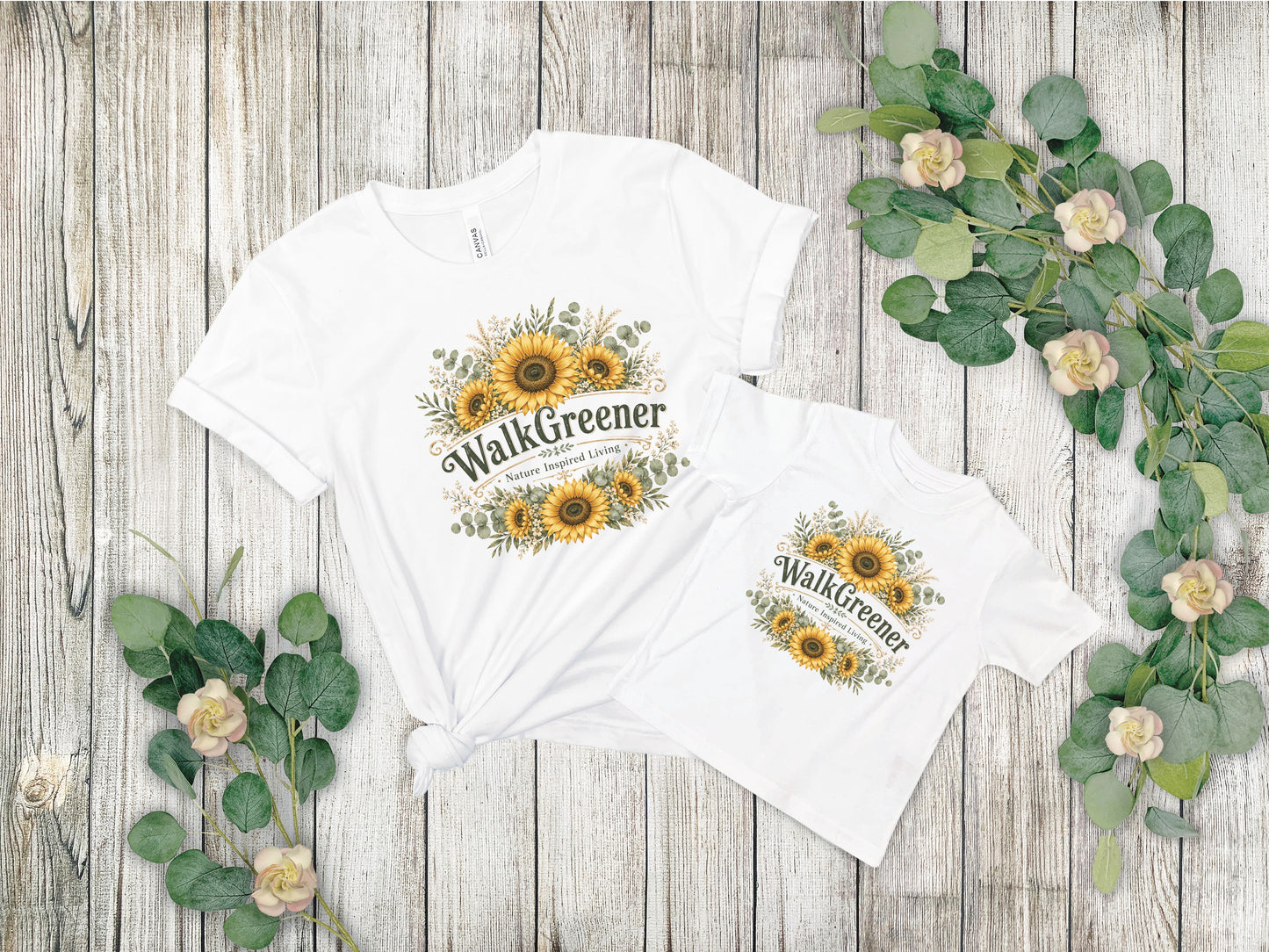 Two white t-shirts with sunflower and greenery graphic that reads "WalkGreener."
