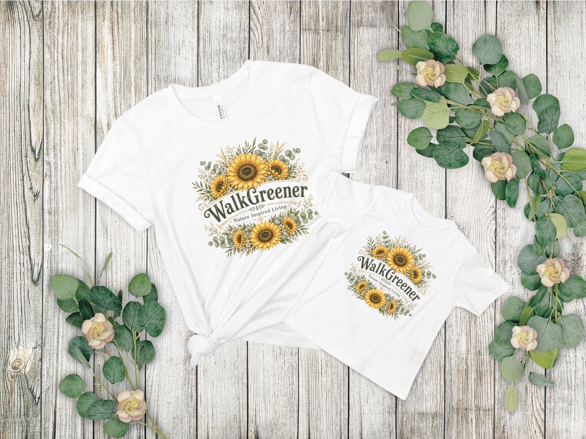 Two white t-shirts with sunflower and greenery graphic that reads "WalkGreener."