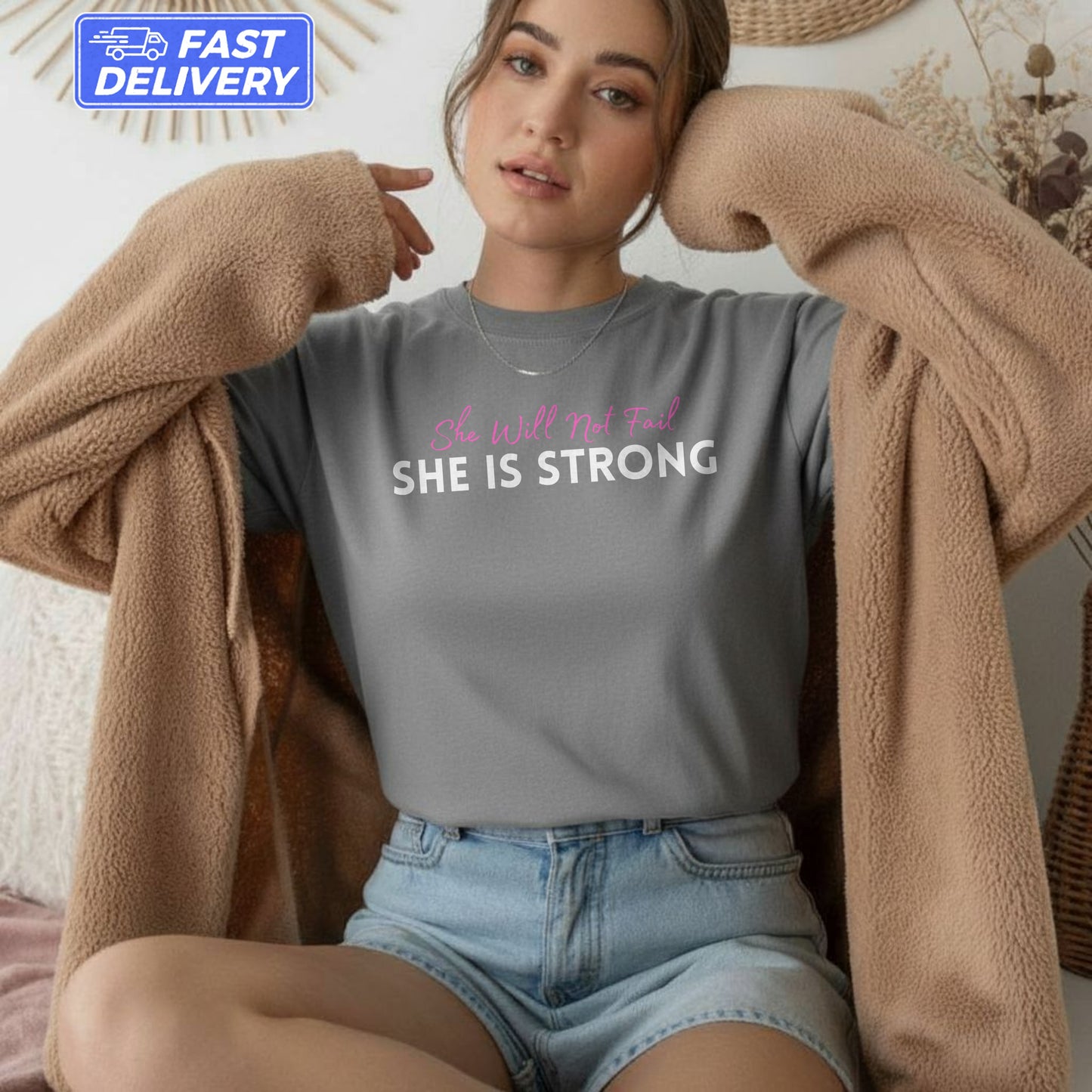 Gray t-shirt with "She Will Not Fail SHE IS STRONG" text, worn by a woman.