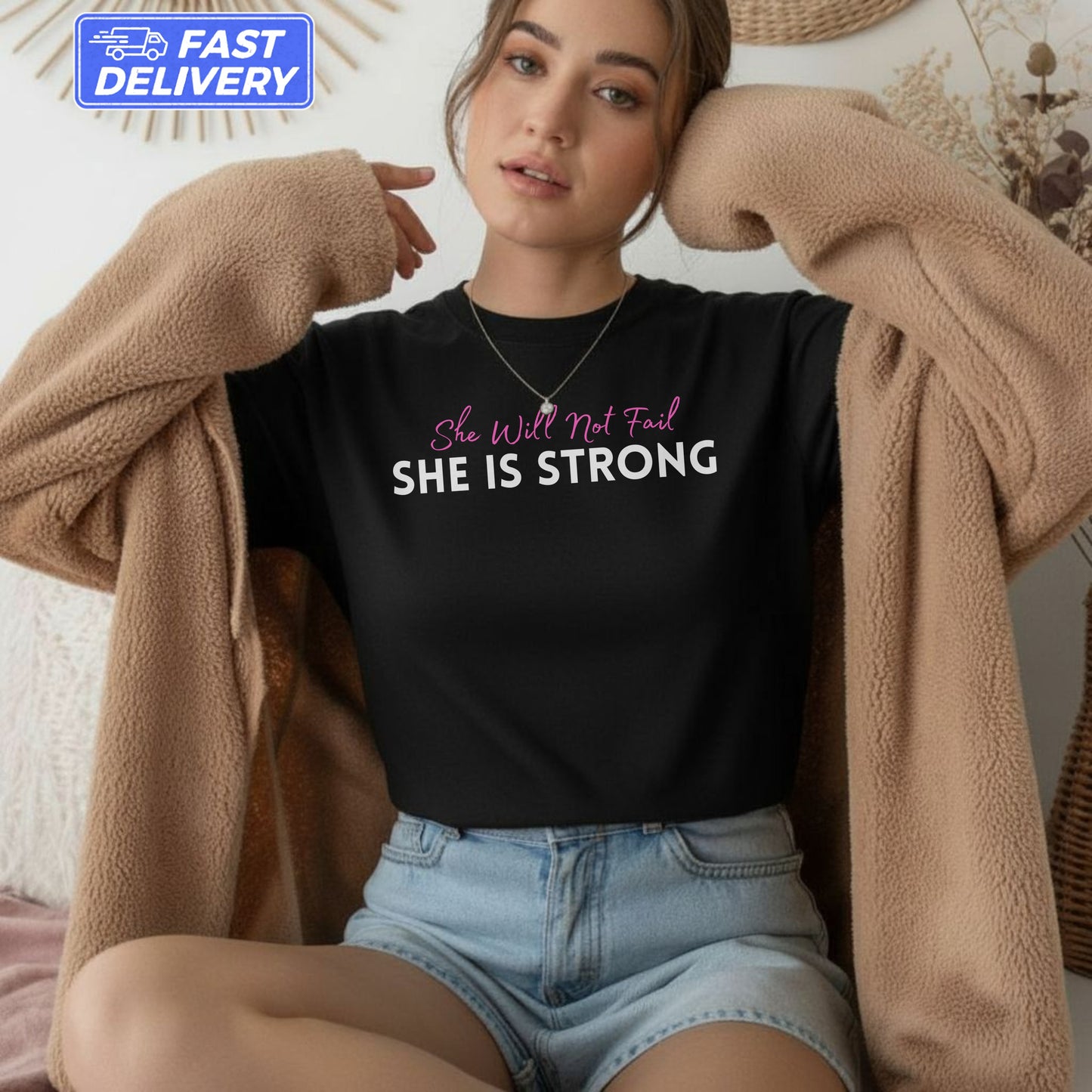 Black t-shirt with "She Will Not Fail SHE IS STRONG" text, worn by a woman.
